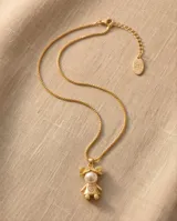 Collar de bronce con cadena fina y dije en forma de silueta de niña con perla sintética en el centro y pequeños cristales incrustados en la zona inferior.