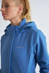 Campera de neopreno color rojo con capucha ajustable, cierre frontal completo y bolsillos laterales. Presenta puños ajustables con velcro y un parche circular decorativo en la manga izquierda.