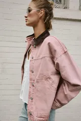 Cazadora de denim efecto lavado color rosado, con cuello solapa de pana marrón, cierre frontal con botones metálicos y bolsillos delanteros de plastrón.