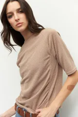 Remera de manga tres cuartos con cuello redondo, confeccionada en tela con estampado geométrico pequeño. Presenta detalles de fruncido en los laterales que aportan movimiento y un ajuste favorecedor.