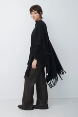 Ruana de tejido de punto en color negro, con diseño de cuello alto y terminaciones con flecos en los bordes.