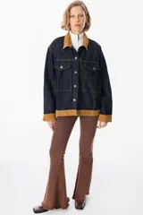 Chaqueta de denim azul oscuro con detalles en pana color tostado en el cuello, puños y ruedo. Presenta cierre frontal con botones metálicos y bolsillos frontales con solapa.