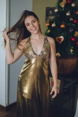 Vestido largo con estampado tie-dye en tonos violeta y fucsia, escote en V con detalles bordados dorados, cut-outs laterales bajo el busto y tirantes finos que se cruzan y atan en la espalda.