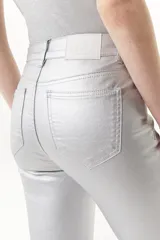 Pantalón jean plateado de tiro medio/alto con silueta levemente acampanada desde la rodilla y aberturas en los tobillos.