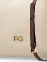 Cartera tipo tote de cuero color crudo con detalles en marrón. Tiene doble asa corta, correa larga extraíble, cierre con broche metálico, logo metálico frontal y bolsillo interno con cierre. Diseñada en Uruguay y fabricada en Brasil.