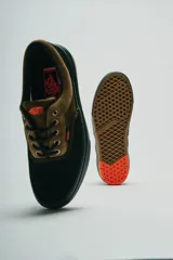 Championes Vans modelo Skate Era Wafflecup, con diseño bicolor en negro y marrón. Presentan una silueta clásica de skate con suela WaffleCup que combina durabilidad y flexibilidad, cordones negros y detalles en color naranja en la lengüeta, plantilla y suela.