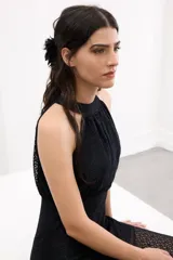 Vestido largo de encaje negro con escote halter, cuerpo ajustado y falda fluida con tajo frontal.