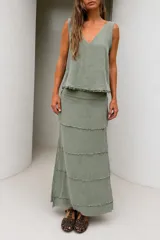 Falda larga color beige de lino tusor, con diseño de recortes en capas con detalles desflecados, de calce relajado y caída natural.