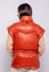 Campera puffer de diseño ochentoso con mangas removibles que permiten convertirla en chaleco. Presenta cuello alto, cierre frontal y cordón ajustable en la cintura.