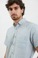 Camisa azul de manga corta, con cuello abotonado y bolsillo en el pecho.