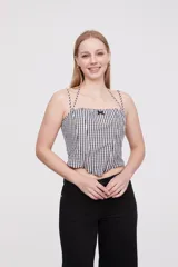 Top corto de escote cuadrado con breteles finos ajustables, confeccionado en tela con estampado de cuadros vichy en blanco y negro. Presenta un pequeño lazo decorativo en el centro del escote y un corte estilo corset con ruedo en punta.