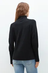 Polera de punto color ladrillo, de cuello alto y mangas largas con cierre en los puños.