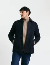 Sobretodo corto de paño en color azul marino, con cuello camisero, cierre frontal mediante botones y manga larga.