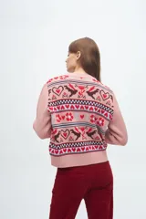 Buzo tejido de punto con diseño jacquard que presenta motivos de corazones, flores y aves en tonos bordó, blanco y celeste. Posee cuello redondo, puños y ruedo acanalados.