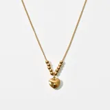 Collar dorado con cadena de eslabones y cuentas esféricas. Dije colgante en forma de corazón.