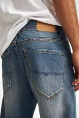 Jean de calce recto, color azul medio, con terminación arremangada.