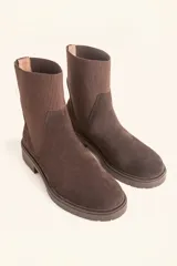 Bota tipo chelsea de gamuza color marrón, con paneles laterales elásticos acanalados y suela de goma track con taco bajo.