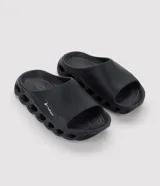 Ojotas tipo slide de la marca Rider, color negro, confeccionadas en PVC. Presentan una sola tira ancha horizontal con el logo de la marca, plantilla anatómica y suela cutout con aberturas laterales para mayor ventilación y ligereza.