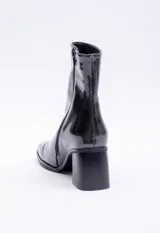 Botín negro de charol con caña media, punta cuadrada, cierre lateral y tacón bloque.