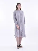 Vestido camisero midi a rayas verticales grises y blancas, con cuello mao y mangas largas abullonadas.