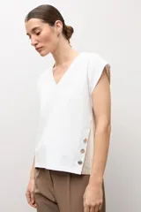 Remera blanca sin mangas con escote en V, detalles de botones en el lateral y espalda de tejido de punto en tono tostado.