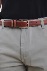 Cinturón de cuero marrón con costuras blancas y hebilla metálica plateada.