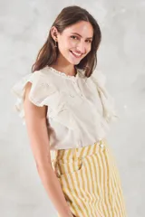 Blusa sin mangas color crema con bordado floral, cuello mao y volados en los hombros.