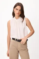 Blusa sin mangas color crema, con cuello alto fruncido y diseño holgado.