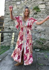 Vestido midi de seda con estampado estilo boho, escote en V, mangas 3/4 con volados y detalle de franja central contrastante. Presenta una cintura elástica y ruedo con volado.