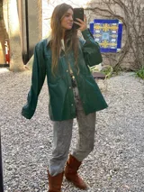 Campera tipo camisa de cuero color verde, con cierre frontal de botones metálicos, cuello clásico y bolsillos frontales con solapa.