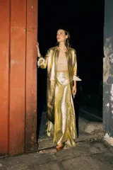 Pollera larga de corte godet, color dorado brillante, con textura de brocato y flecos en el ruedo.