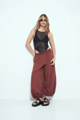 Pantalón ancho estilo Aladdin de tiro bajo, color marrón rojizo, con cintura elastizada y puños ajustados en los tobillos.