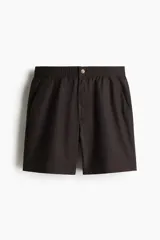 Short de popelina de algodón en color marrón oscuro, con cintura elástica, cierre frontal con botón, bolsillos laterales al bies y bolsillos traseros insertados con botón.