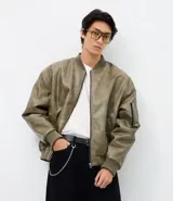 Campera bomber de poliuretano con acabado efecto cuero, cuello redondo, cierre frontal con cremallera, bolsillos delanteros y bolsillo utilitario en la manga. Presenta puños y ruedo elásticos, con forro interior en contraste.