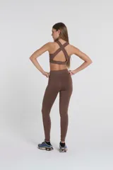 Top deportivo marrón con breteles anchos cruzados en la espalda y banda elástica inferior.