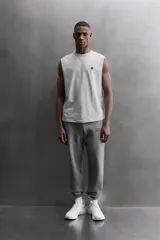 Camiseta sin mangas gris de corte regular fit, con cuello redondo. Presenta un bordado de un guante de boxeo en el pecho y un parche con logo en la parte inferior.