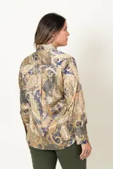 Camisa de satén con estampado paisley en tonos mostaza, azul y marrón. Tiene cuello camisero, mangas largas con puños abotonados y cierre frontal con botones dorados.