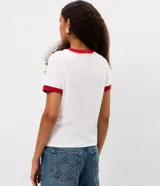 Remera de algodón blanca de corte ajustado, con cuello redondo y ribetes en las mangas de color rojo. Cuenta con un estampado frontal localizado del logo de Supergirl.