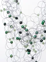 Collar de cuentas azules y celestes con hilos plateados y cierre de cordón negro.