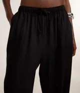 Pantalón de corte holgado y fluido, color negro, con cintura elástica y lazo ajustable. Confeccionado en una mezcla de viscosa y lino.