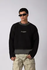 Sweater de punto acanalado con diseño degradado de negro a gris en el cuello y el ruedo. Presenta un corte regular y un pequeño bordado central en el pecho.