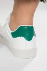 Zapatillas acordonadas de cuero color blanco con puntera de gamuza gris y detalles en verde.