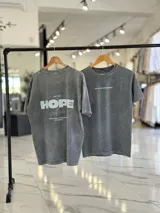 Remera oversize gris con efecto gastado, mangas cortas y estampa con texto blanco en el frente y en la espalda.