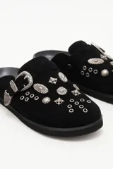 Zueco de cuero descarne negro con diseño de estilo western, decorado con tachas metálicas plateadas y una hebilla lateral ajustable.