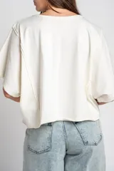 Remera oversize de algodón blanco crudo, con cuello redondo y mangas cortas anchas de corte relajado.
