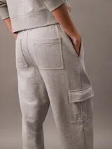 Pantalón de chándal gris de corte holgado con bolsillos cargo laterales, cintura elástica con cordón y bajos elásticos. Confeccionado en felpa de mezcla de algodón.