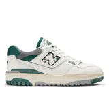 Championes New Balance modelo 550, de diseño retro inspirado en el básquetbol. Presenta una base de cuero blanco con detalles en verde oscuro y gris, incluyendo el logo 'N' con efecto desgastado y suela de goma con acabado envejecido.