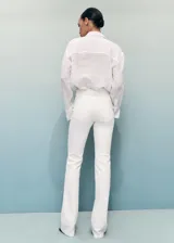 Jeans Fiona de tiro medio y corte flare con bajo deshilachado, confeccionados en tejido denim de algodón con elasticidad. Presentan diseño clásico de cinco bolsillos, trabillas para cinturón y cierre delantero con cremallera y botón metálico.