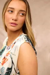 Blusa sin mangas de diseño fluido, color crudo con estampado botánico y floral en tonos azules, verdes, amarillos y naranjas.