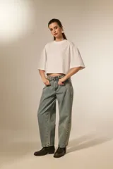 Remera blanca de corte holgado con mangas 3/4 y cuello redondo a la base. Presenta un diseño con apliques de studs metálicos distribuidos por toda la prenda.